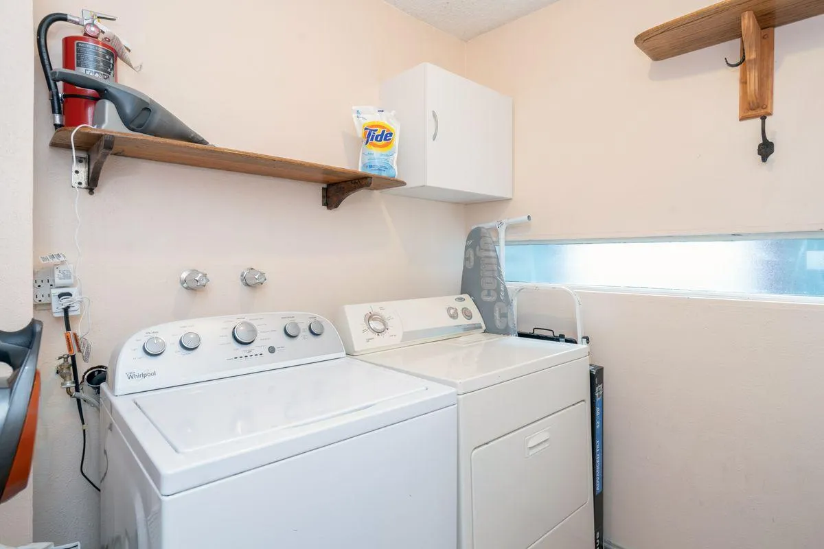 The image displays a tidy laundry nook with a washing machine, dryer, and a shelf lined with laundry supplies. The space is compact and optimized for utility, underscoring the convenience of having in-unit laundry for guests to refresh gear and clothing after exploring Telluride.